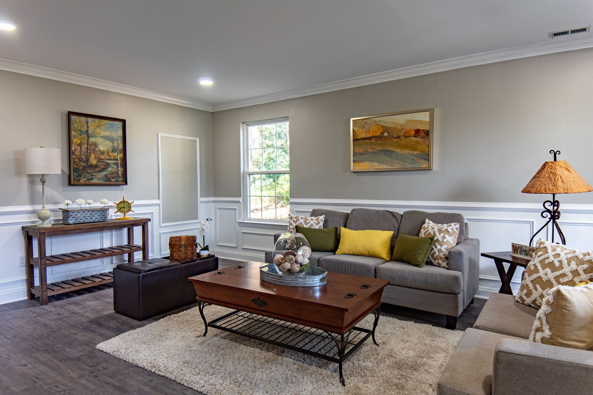 Spacious living room featuring modern decor, grey sofas, and vibrant artwork.