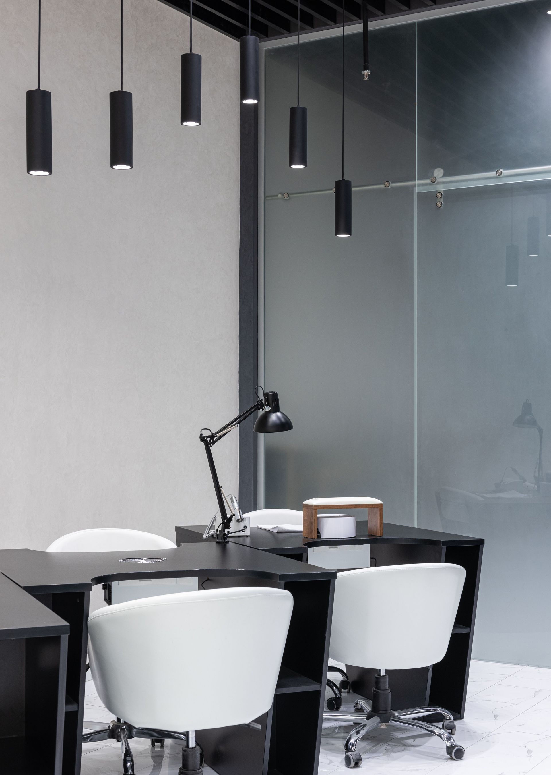 A sleek modern office interior featuring elegant black furniture and pendant lights.
